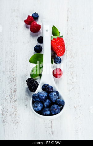 Beeren mit Löffel auf hölzernen Hintergrund. Erdbeeren, Himbeeren und Heidelbeeren. Gesundheit, Ernährung, Gartenbau, Ernte-Konzept Stockfoto