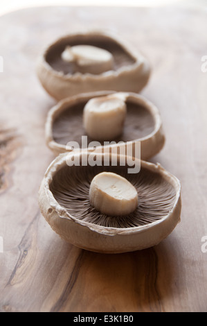 Drei Portobello Pilze auf einem rustikalen Schneidebrett Stockfoto