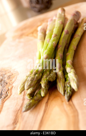 Frische Bio-Spargel gebündelt zusammen auf ein Schneidbrett aus Holz Stockfoto