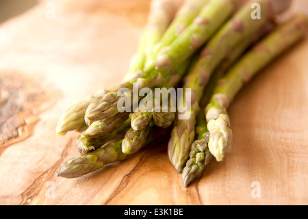 Frische Bio-Spargel gebündelt zusammen auf ein Schneidbrett aus Holz Stockfoto