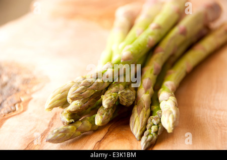 Frische Bio-Spargel gebündelt zusammen auf ein Schneidbrett aus Holz Stockfoto