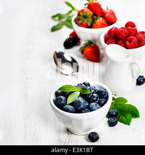 Beeren in Schalen auf hölzernen Hintergrund. Erdbeeren, Himbeeren und Heidelbeeren. Gesundheit, Ernährung, Gartenbau, Ernte-Konzept Stockfoto