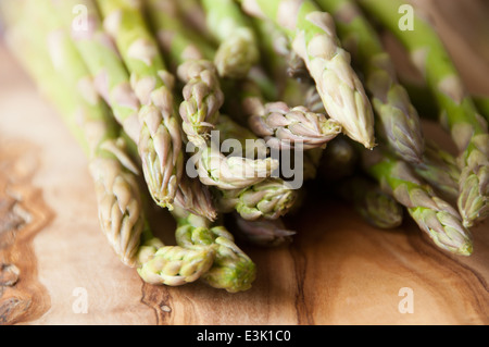 Frische Bio-Spargel gebündelt zusammen auf ein Schneidbrett aus Holz Stockfoto