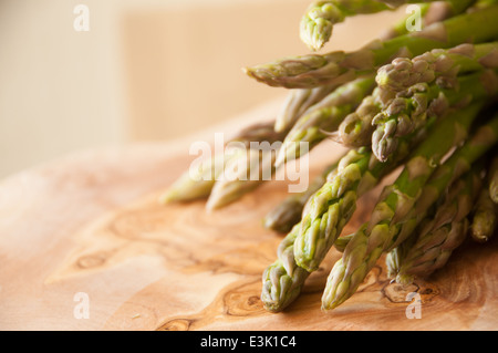 Frische Bio-Spargel gebündelt zusammen auf ein Schneidbrett aus Holz Stockfoto