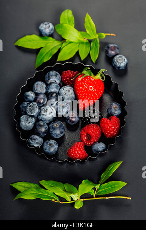 Frische Beeren auf dunklem Hintergrund. Erdbeeren, Himbeeren und Heidelbeeren. Gesundheit, Ernährung, Gartenbau, Ernte-Konzept Stockfoto