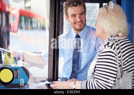 Ältere Frau einsteigen in Bus und Ticket kaufen Stockfoto