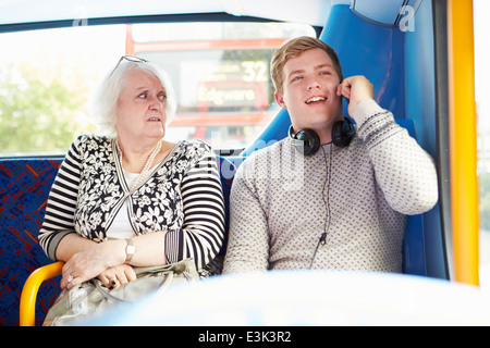 Mann, die Passagiere auf Busfahrt mit Telefonanruf zu stören Stockfoto