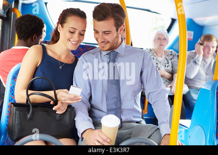 Geschäftsmann und Frau betrachten Handy auf Bus Stockfoto