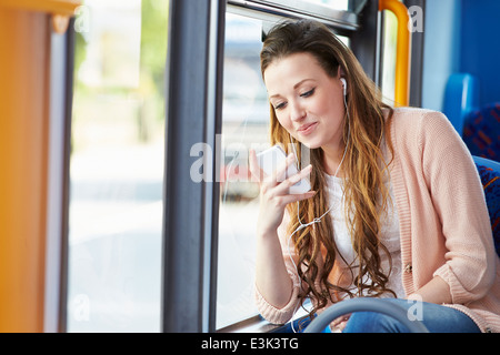 Junge Frau trägt Kopfhörer Musik hören auf Bus Stockfoto