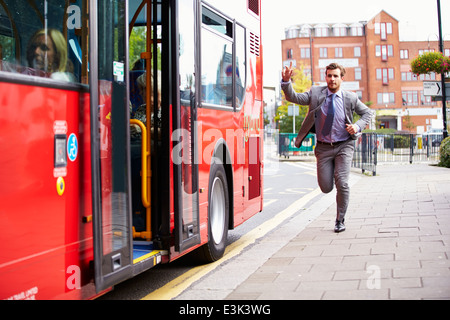 Geschäftsmann laufen, Bushaltestelle zu fangen Stockfoto