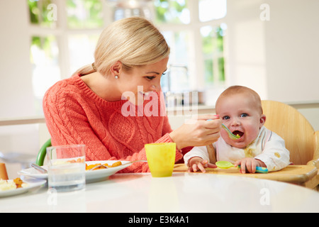 Mutter Fütterung Baby im Hochstuhl sitzen, bei den Mahlzeiten Stockfoto