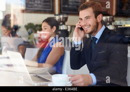 Geschäftsmann mit Handy und Laptop im Café Stockfoto