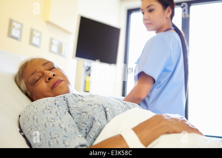 Krankenschwester beobachtete schlafenden Senior Woman Patient im Krankenhaus Stockfoto