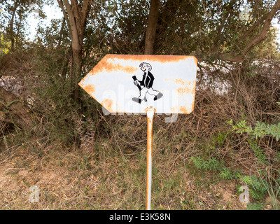 Ein rostendes Metall Fußweg Schild zeigt links zeigt ein Beispiel für ein Lächeln auf den Lippen zu Fuß Mann mit Stock Stockfoto