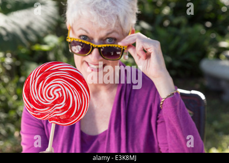 Glücklich Reife Frau genießen ihre Sonnenbrille und übergroßen Lollipop, USA Stockfoto