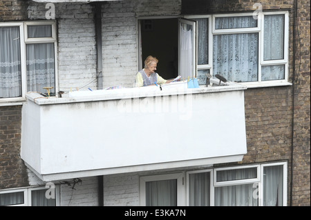 Ältere Dame hängen Wäsche zum Trocknen auf dem Balkon in London Stockfoto
