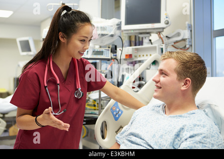 Junge männliche Patienten sprechen, Weiblich Krankenschwester In der Notaufnahme Stockfoto