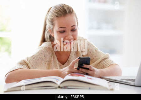 Teenager-Mädchen SMS während des Studiums auf Laptop Stockfoto