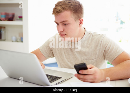 Teenager senden SMS während des Studiums auf Laptop Stockfoto