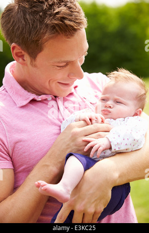 Stolzer Vater Holding Tochter im Garten Stockfoto