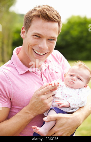 Stolzer Vater Holding Tochter im Garten Stockfoto