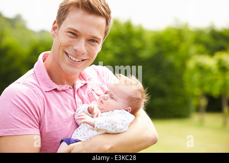 Stolzer Vater Holding Tochter im Garten Stockfoto