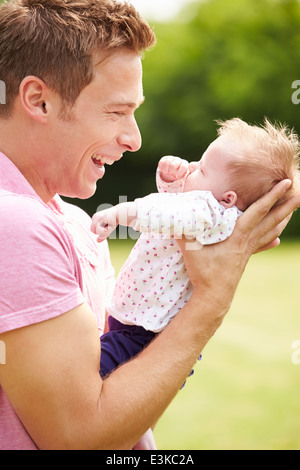 Stolzer Vater Holding Tochter im Garten Stockfoto