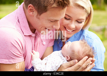 Stolze Eltern halten Baby Tochter im Garten Stockfoto