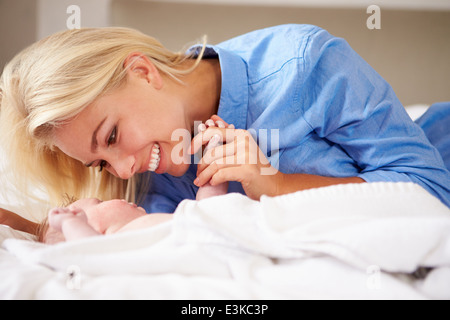 Mutter mit Babymädchen spielen, als sie zusammen im Bett liegen