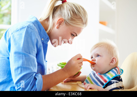 Mutter Fütterung Baby Boy im Hochstuhl Stockfoto