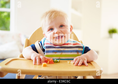 Baby Boy Verzehr von Obst im Hochstuhl Stockfoto
