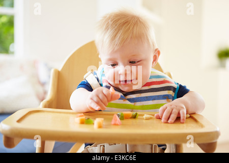 Baby Boy Verzehr von Obst im Hochstuhl Stockfoto