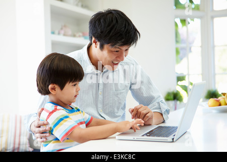 Asiatischen Vater helfen Sohn Laptop zu Hause verwenden Stockfoto