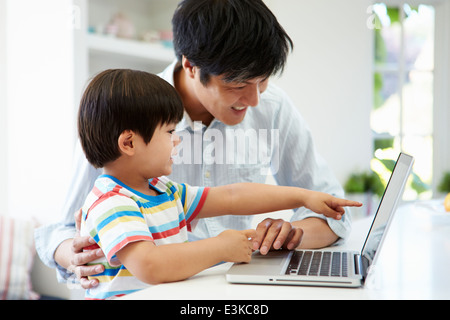 Asiatischen Vater helfen Sohn Laptop zu Hause verwenden Stockfoto