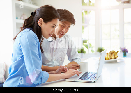 Asian paar Blick auf Laptop In Küche Stockfoto