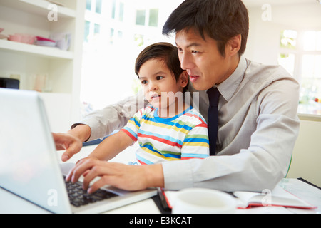 Vater mit Sohn von zu Hause aus Arbeiten beschäftigt Stockfoto