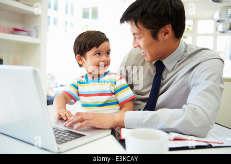 Vater mit Sohn von zu Hause aus Arbeiten beschäftigt Stockfoto