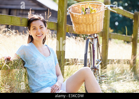 Asiatische Frau ruht von Zaun mit alten altmodischen Zyklus Stockfoto