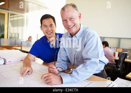 Architekten, die Pläne In modernen Büro gemeinsam studieren Stockfoto