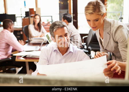 Zwei Kollegen, die Arbeiten am Schreibtisch mit treffen im Hintergrund Stockfoto