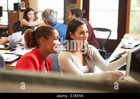 Zwei Kollegen, die Arbeiten am Schreibtisch mit treffen im Hintergrund Stockfoto
