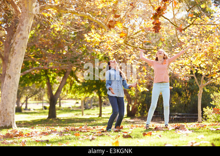 Zwei Mädchen, die Blätter im Herbst In die Luft werfen Stockfoto