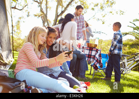 Zwei Mädchen mit Handy auf Camping Familienurlaub Stockfoto