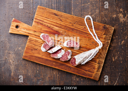 Salami Wurst auf Holzbrett auf dunklem Hintergrund Stockfoto