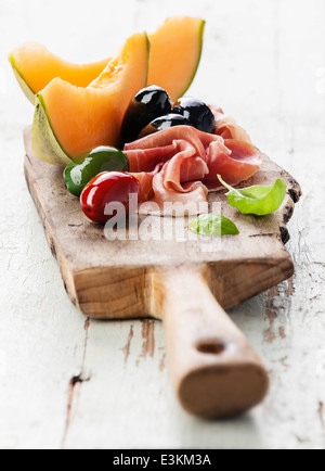 Schinken, Scheiben Melone Melone und Oliven auf Schneidebrett Stockfoto