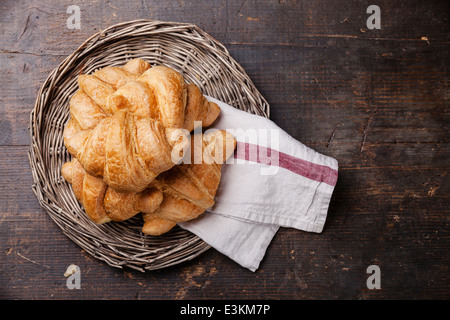 Croissants in Wicker Tablett auf dunklem Holz Stockfoto