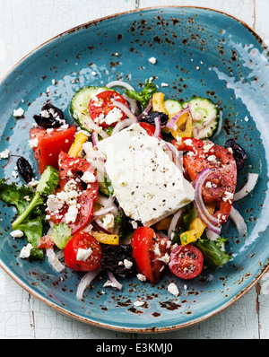 Griechischer Salat mit Fetakäse und sonnengetrocknete Oliven auf blauem Hintergrund Stockfoto