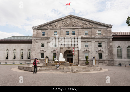 Ein Foto mit Haupteingang Rideau Hall. Ein paar Touristen fotografieren außerhalb der Vorderseite des Rideau Hall. Flaggen sind auf Halbmast. Stockfoto