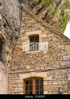 Gegen die Klippe: ein Haus passt sich an die Felswand. Ein Haus scheint nur die Hälfte eines Hauses, wie es in der Nähe der Steilküste schmiegt Stockfoto