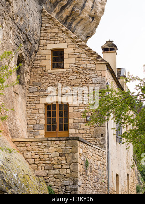 Gegen die Klippe: ein Haus passt sich an die Felswand. Ein Haus scheint nur die Hälfte eines Hauses, wie es in der Nähe der Steilküste schmiegt Stockfoto